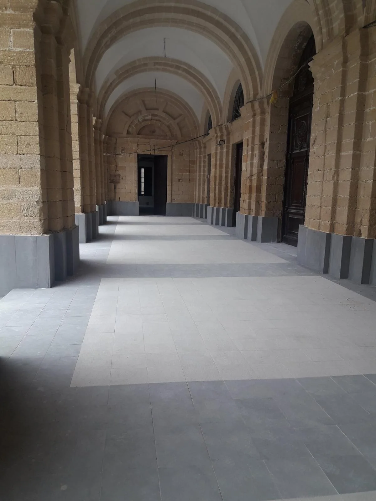 Exterior application: grey plinth panels and base courses lining a vaulted stone arcade