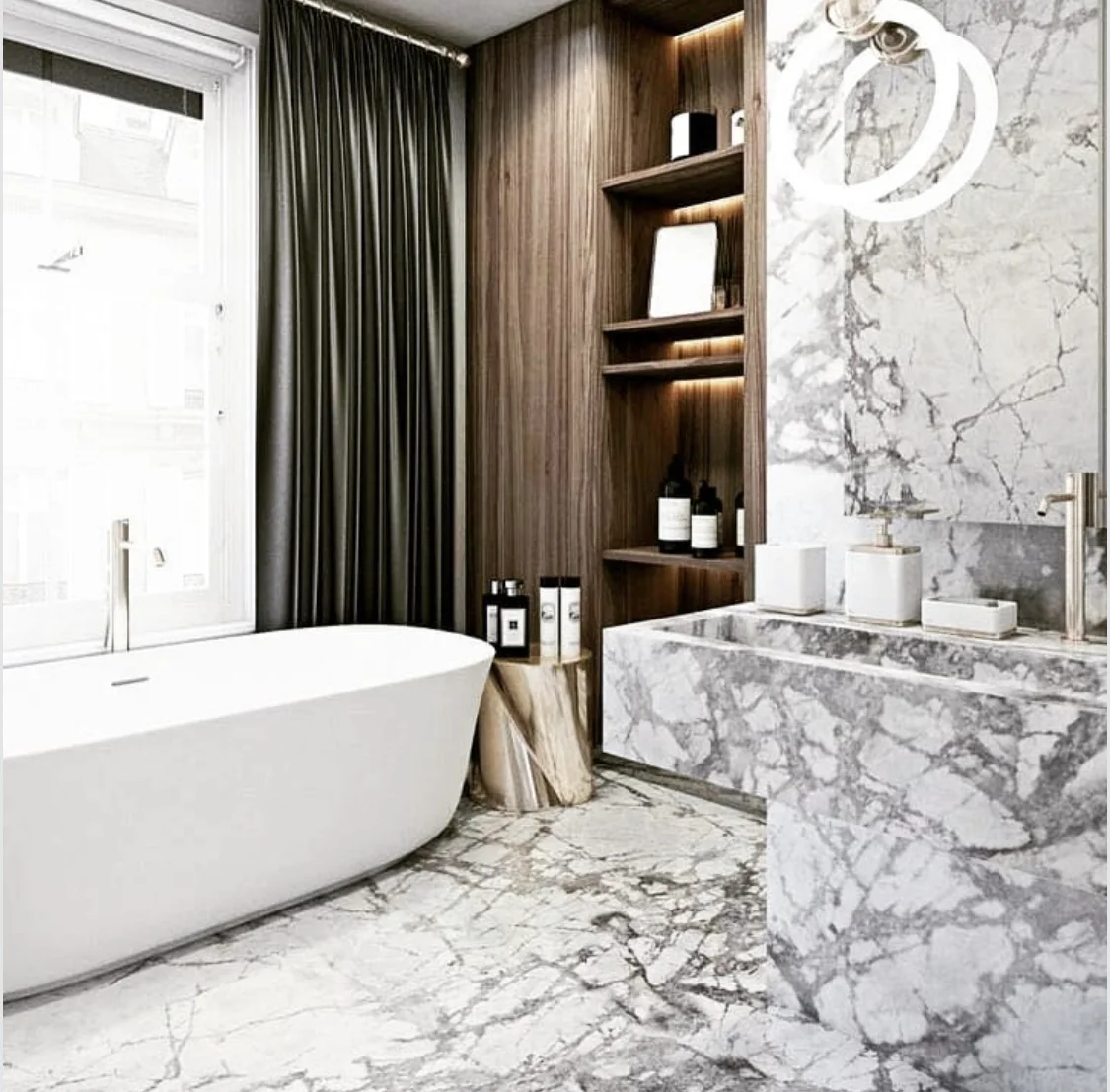 Bathroom with veined marble across the floor, vanity, and wall beside a freestanding bath