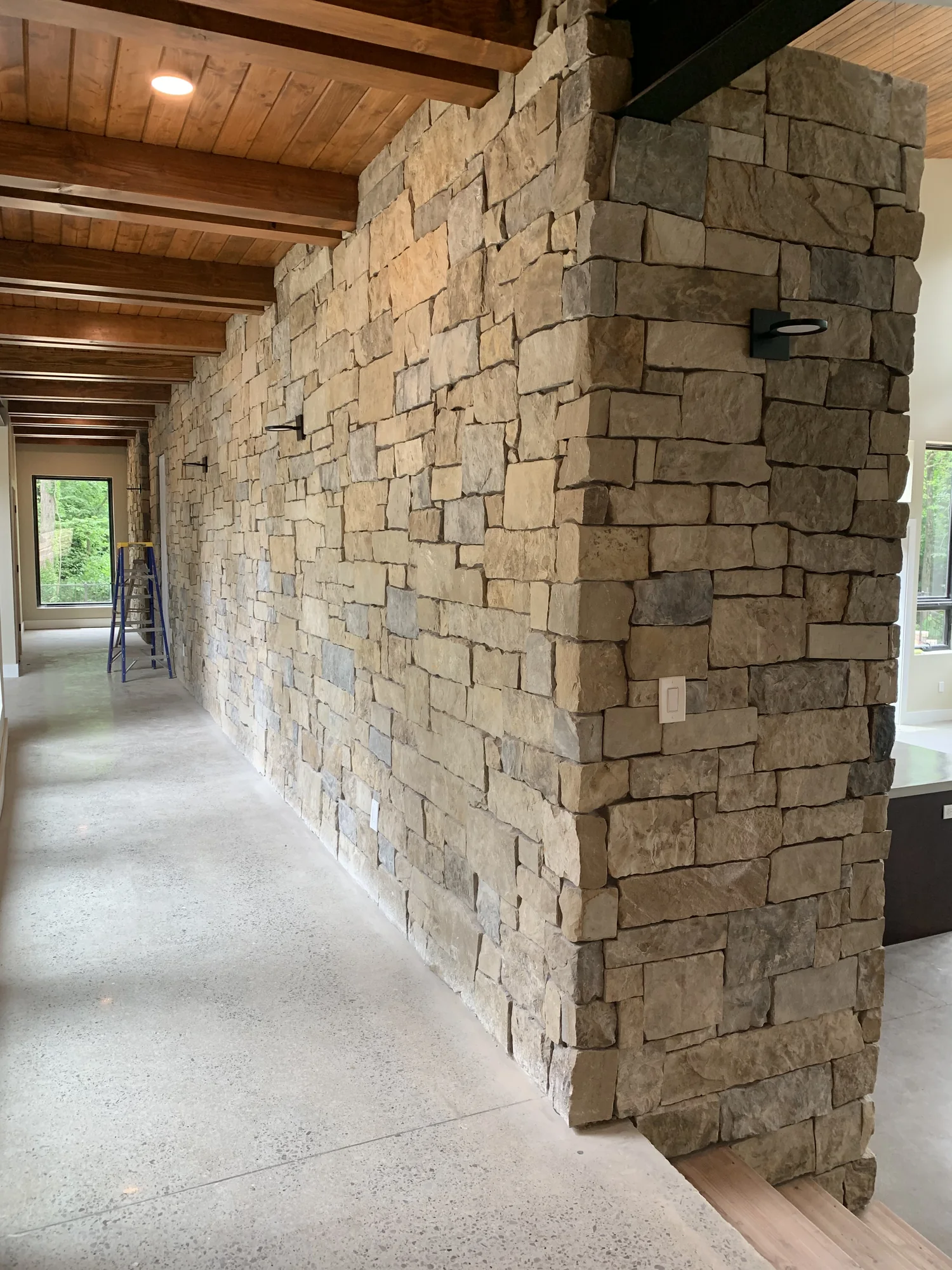 Natural stone masonry showing varied block sizes and texture along a covered walkway