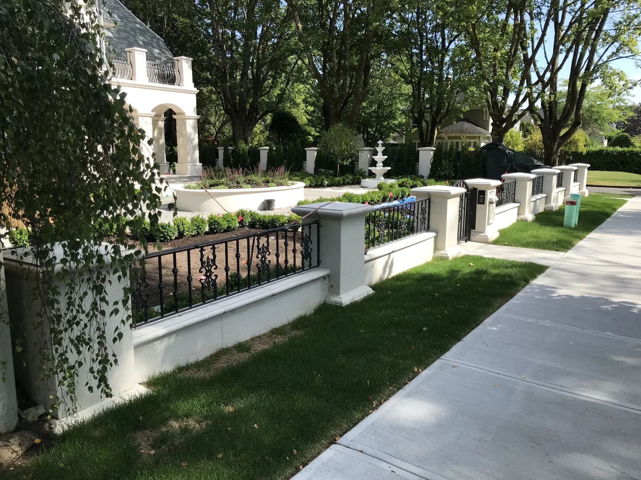 Repeated capped piers along a metal garden fence