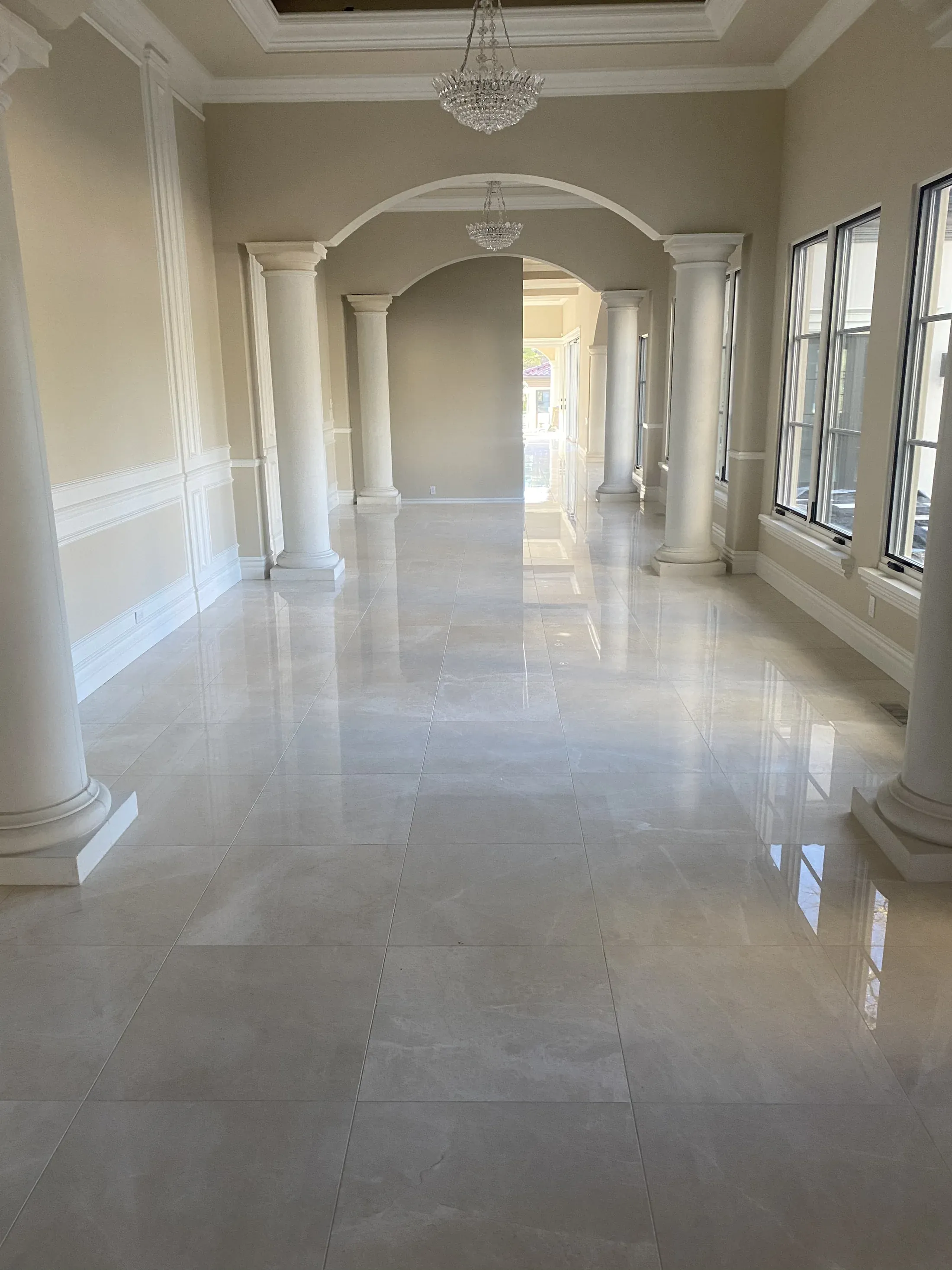 White baseboards and lower-wall trim through an arched interior hallway