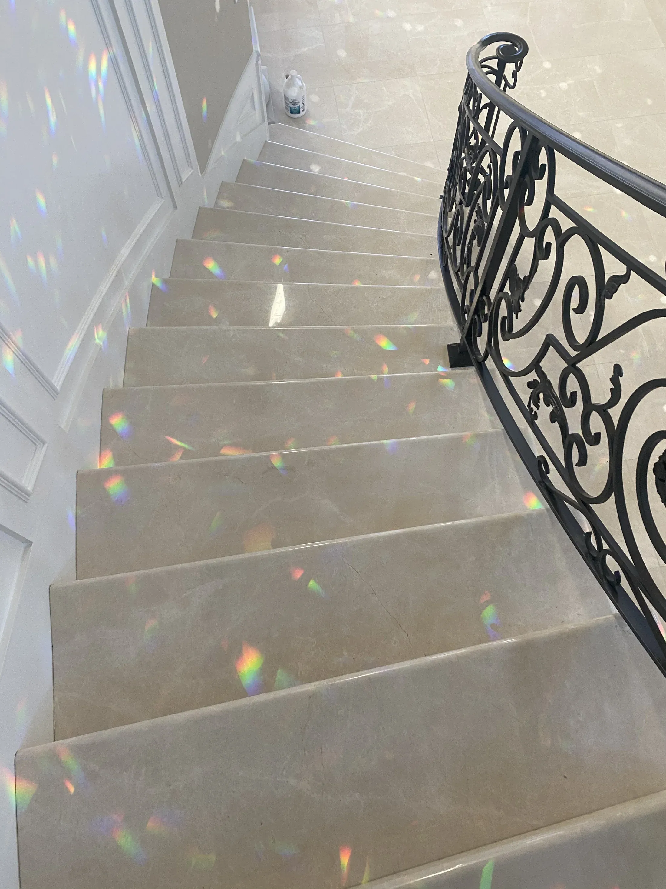 Polished stone staircase beside a decorative metal railing