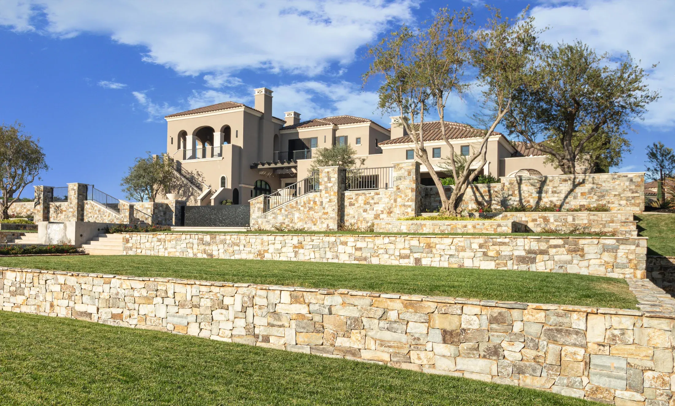 Residence with natural stone veneer across landscape walls and pillars